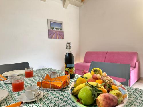 a table with a plate of fruit and a bottle of wine at Corte Ludovica in Martano