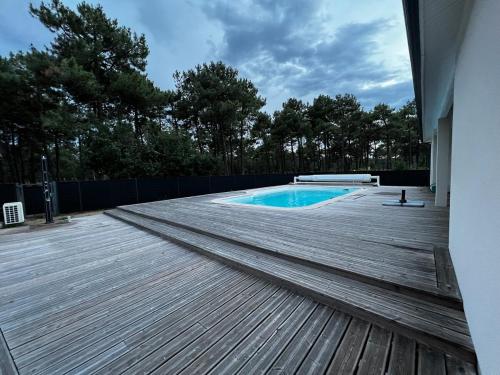 - une piscine entourée d'une terrasse en bois dans l'établissement La Gaboline villa 9p avec piscine, à Montalivet-les-Bains