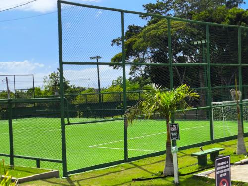 a tennis court with a fence and a palm tree at Residencial Girassol Outeiro in Porto Seguro