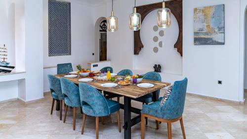 a dining room with a wooden table and blue chairs at Domaine Terra Cotta - Villa de luxe avec piscine sans vis-à-vis in Souk el Had