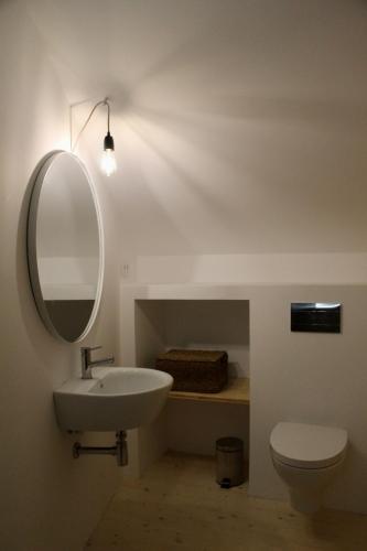 a bathroom with a sink and a mirror and a toilet at Casa das Ribeiras in Azoia de Baixo
