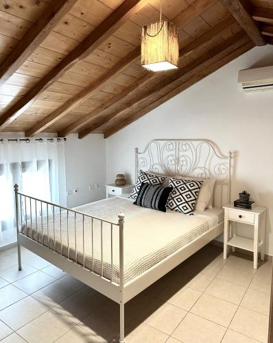 a bedroom with a white bed and a wooden ceiling at Restia House in Steni Vala Alonissos