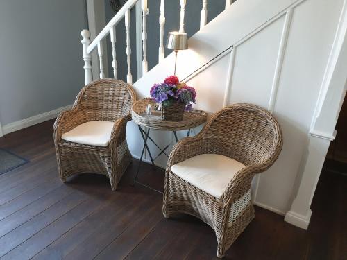 two wicker chairs and a table with flowers on it at Budget in Westerland (Sylt)