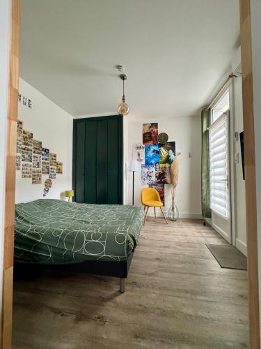 - une chambre avec un lit vert et une chaise jaune dans l'établissement La bulle d'Angouleme, à Angoulême