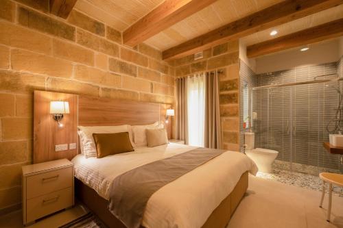 una camera da letto con un letto grande e un muro di pietra di Silla Boutique B&B a Xagħra