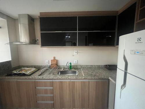 a small kitchen with a sink and a refrigerator at Conforto e lazer na rua do hospital Albert Einstein! in Goiânia