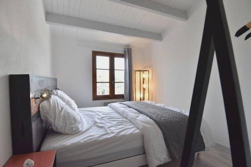 ein Schlafzimmer mit einem weißen Bett mit einem Fenster in der Unterkunft Maison à 300 m de la plage et centre avec piscine in La Couarde-sur-Mer