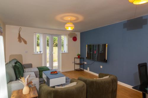 a living room with a couch and a tv at The Vogue Stay, 3 Bedrooms, 2 bathrooms, Ideal for JR & Oxford Hospitals, FREE CarPark, Conveniently located for Ring Road access, 2 miles from Oxford City Centre easy car & bus route in Oxford