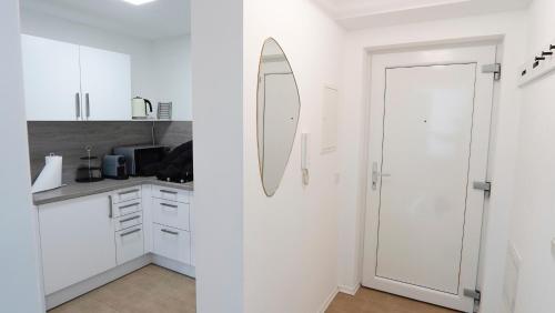 a white kitchen with a mirror on the wall at Apartment Passau C - Gargen, Stilvoll, Modern & Cozy im Zentrum von Passau in Passau