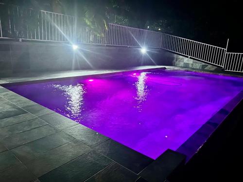 a swimming pool with purple lights in the night at Bleu Soleil in Le Morne-Vert