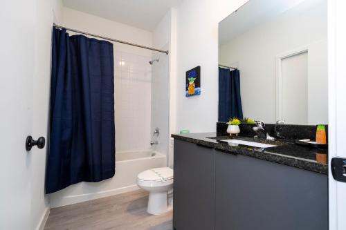 a bathroom with a toilet and a blue shower curtain at Luxury 3 Bed Home up to 8 guests- The Hub - 3236 TT in Orlando