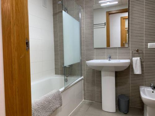 ein Badezimmer mit Waschbecken, Spiegel und Badewanne in der Unterkunft Sunrise Beach Apartment Playa Puerto de Sagunto in Puerto de Sagunto