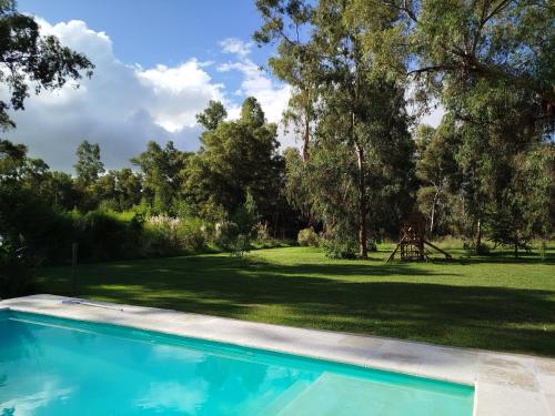 a swimming pool in front of a yard with trees at Los Horneros in San Miguel del Monte