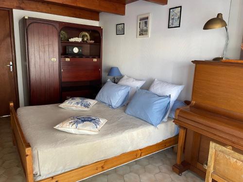 1 dormitorio con cama con almohadas azules y piano en La maison des courlis, en Rivedoux-Plage