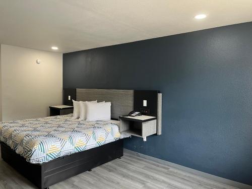 a bedroom with a bed and a blue wall at Motel 6 Vicksburg, MS in Vicksburg
