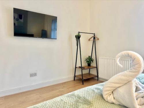 ein Schlafzimmer mit einem Bett und einem Fernseher an der Wand in der Unterkunft 4 Bed Home Northampton, FreeParking, Superfast WiFi, 5TVs in Northampton