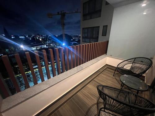 a balcony with two chairs and a view of a city at night at 1 bed Apartment in Osu - Accra, Ghana - Solaris Apartments in Accra