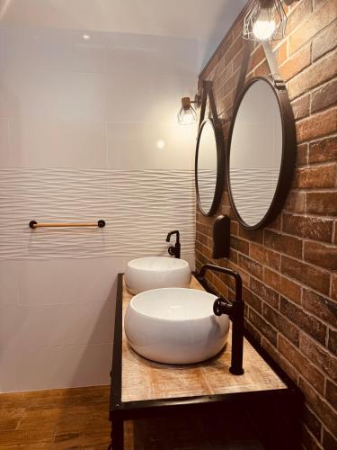 La salle de bains est pourvue de 2 lavabos et d'un mur en briques. dans l'établissement Calme et reposant en hypercentre, à Romans-sur-Isère
