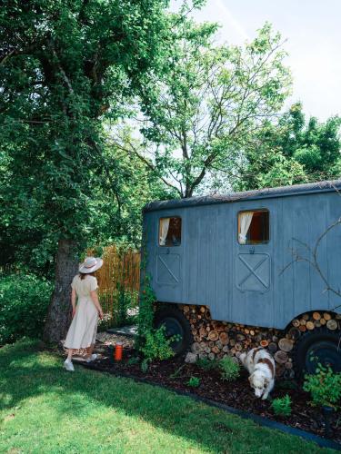 a woman standing next to a blue trailer with a dog at Ubytování Maringote in Doubravice
