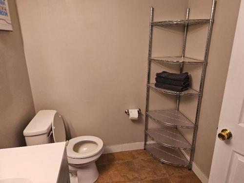 a bathroom with a toilet and a shelf with towels at Liberty hill Executive Inn in Zephyrhills
