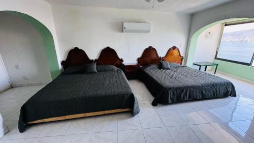 a bedroom with two beds and a window at Casa Jade in Acapulco