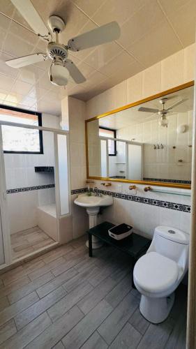 a bathroom with a toilet and a sink and a ceiling fan at Casa Jade in Acapulco