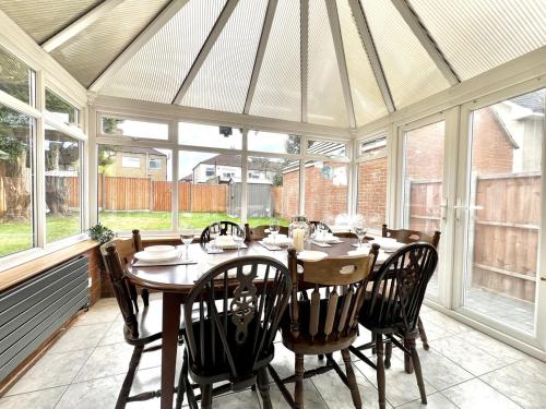 a dining room with a table and chairs in a conservatory at 4 Bedroom Detached Hse, 102 sq mtrs, with 2 Bathrooms, 3 Toilets and Free Parking in Hemel Hempstead
