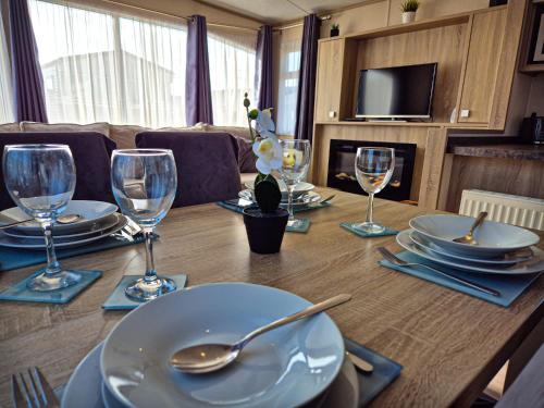 a wooden table with plates and wine glasses on it at Birchington Vale - 2 Bedroom Holiday Home in Margate