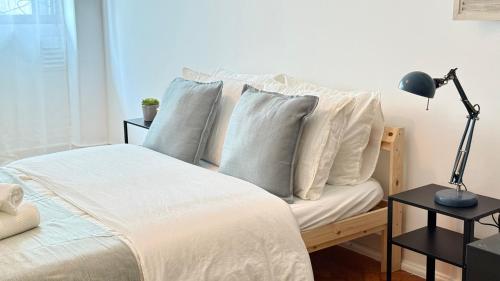 a bedroom with a bed with white pillows and a lamp at Alameda Urban Room in Lisbon