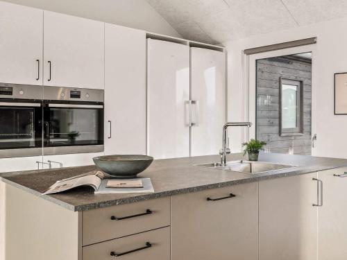 a kitchen with white cabinets and a bowl on a book at 5 star holiday home in Nørre Nebel in Nørre Nebel