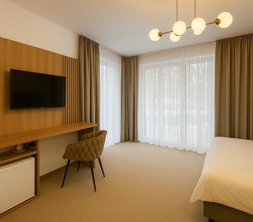 Una habitación de hotel con una cama y un escritorio con televisión. en Resort Eden Premium Sauna, jacuzzi, en Jastrzębia Góra