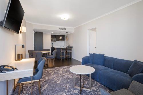 a living room with a blue couch and a kitchen at Hotel Grand Chancellor Brisbane in Brisbane