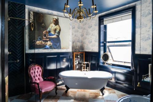 a bathroom with a tub and a painting and a chair at Vintage townhouse, wood burner, leafy garden, close to the beach in Margate