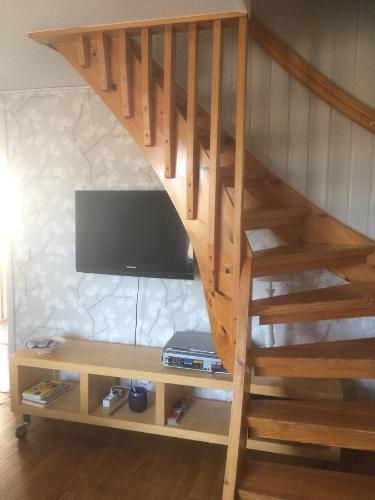 a wooden staircase with a tv and a wooden shelf at Farbror Alfreds Stuga Sjöutsikt in Köpingsvik