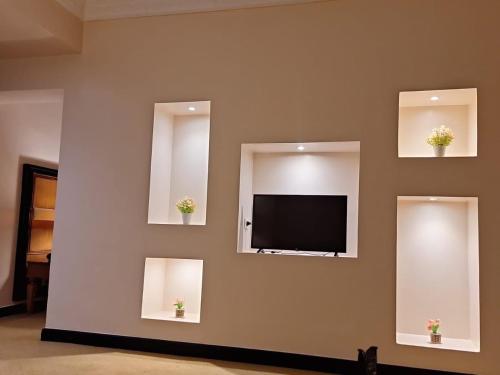 a wall with two mirrors and a tv on a wall at Paradise Home City Stars in Cairo