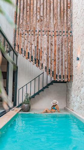 a woman laying in a swimming pool next to a staircase at 2 Bohemian Bliss Villas-2 Pv Pool-Concierge 1A-1B in Tulum