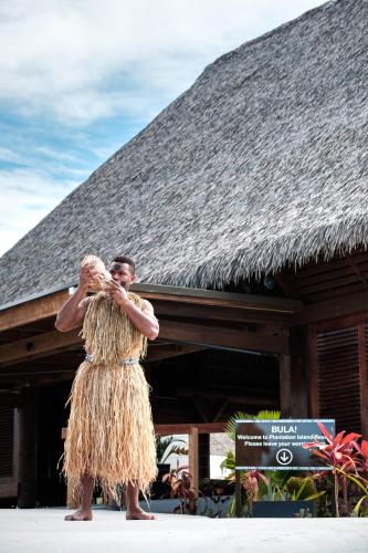 a man in a straw dress standing in front of a building at Plantation Island Resort in Malolo Lailai