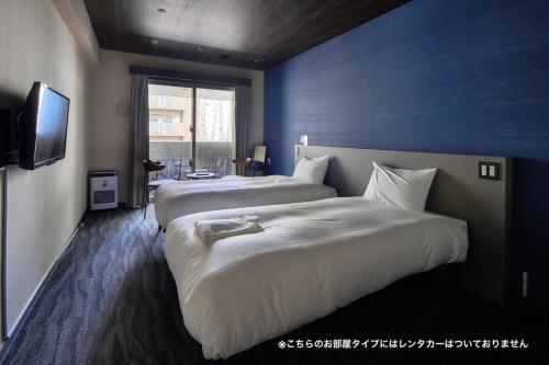 a hotel room with two beds and a television at BbyC Hotel 那覇 レンタカー付ホテル in Naha