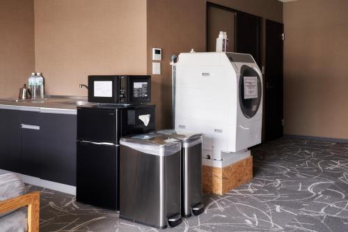 a kitchen with a machine and a trash can at BbyC Hotel 那覇 レンタカー付ホテル in Naha