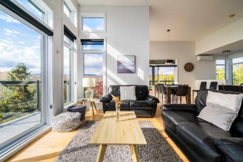 ein Wohnzimmer mit einer schwarzen Ledercouch und einem Tisch in der Unterkunft Le Saint-Laurent in Petite-Rivière-Saint-François