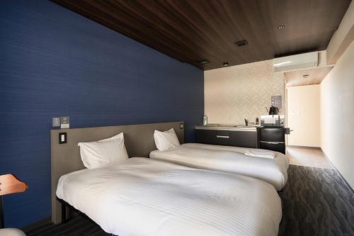 two beds in a small room with a kitchen at BbyC Hotel 那覇 レンタカー付ホテル in Naha