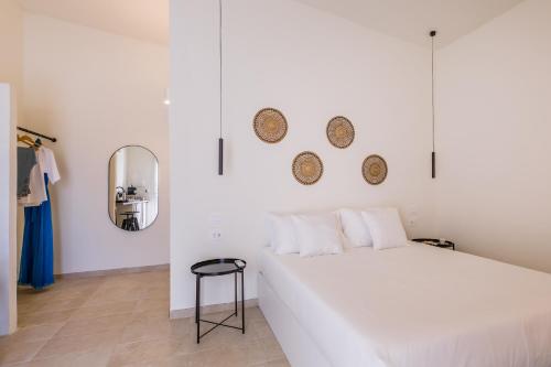 Un dormitorio blanco con una cama blanca y un taburete. en Ziran Resort, en Noto