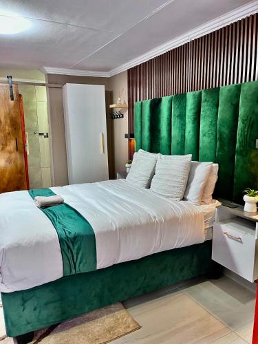 a bedroom with a large bed with a green headboard at Executive Galaxy Guest House Nkowankowa in Nkowakowa