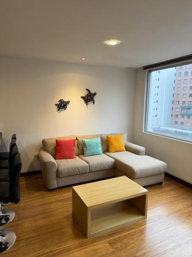 a living room with a couch with colorful pillows at Finlandia Park Suite in Quito