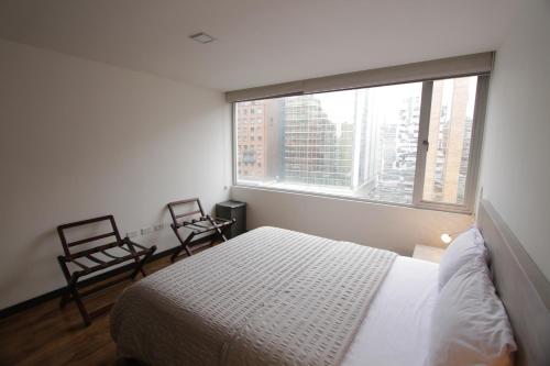 a bedroom with a bed and two chairs and a window at Finlandia Park Suite in Quito