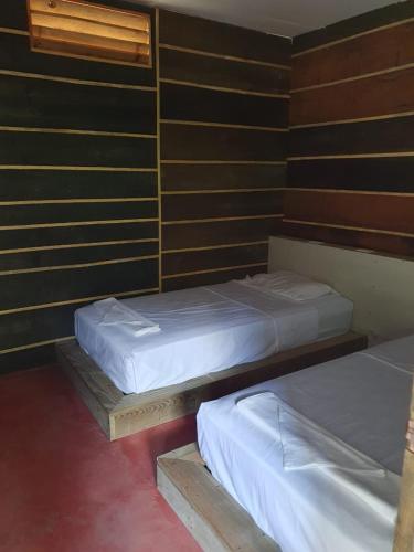 two twin beds in a room with wooden walls at Rustik Hostal in Lanquín