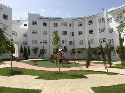 a large white building with a playground in front of it at Relaxing Pool view 2 bed room Apartment in Fnidek