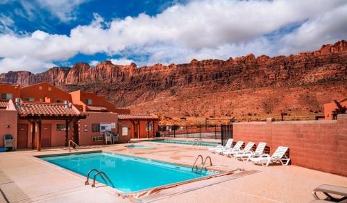 a pool with chairs and a mountain in the background at Moab Adventure Basecamp in Moab