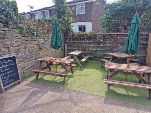 a group of picnic tables with umbrellas next to a wall at The Church House Inn in Bollington