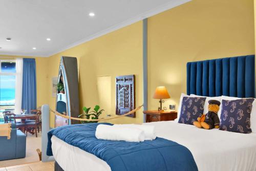 a bedroom with a large bed with a blue headboard at Absolute Beachfront l Couples Getaway in Blue Bay 